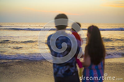 Blurred silhouette of young happy and beautiful Asian Korean couple holding baby girl daughter enjoying sunset beach together Stock Photo