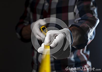 Blurred yellow retractable tape measure in hands of workman in checkered shirt, close up Stock Photo