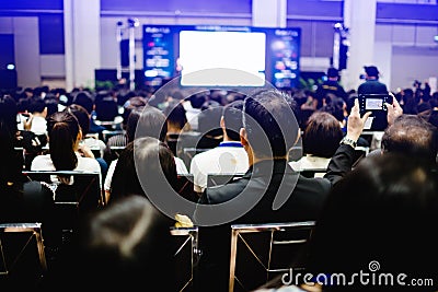 Blurry of auditorium for shareholders` meeting or seminar event with projector and white screen, many business people listening o Stock Photo