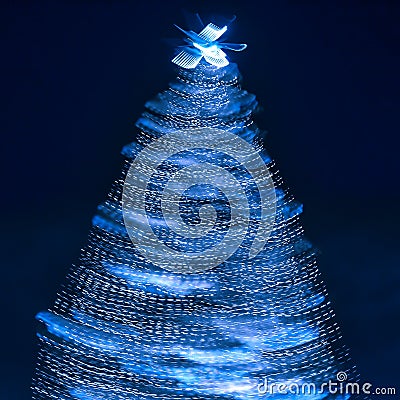 Blurry creative lighted christmas tree in monochrome classic blue palette on a dark background in trendy color of 2020. Xmas and Stock Photo