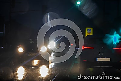 Blurry glare from headlights on windshield in bad rainy weather at night Stock Photo