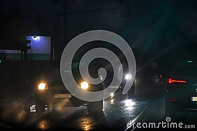 Blurry glare from headlights on windshield in bad rainy weather at night at traffic light Stock Photo