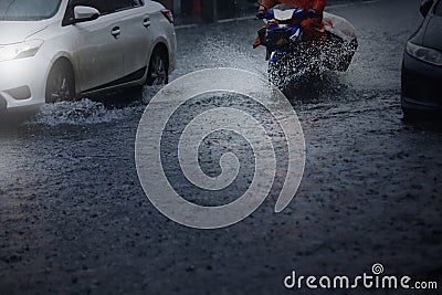 Blurry of motorcycle and cars run through flood water after hard rain fall. Stock Photo