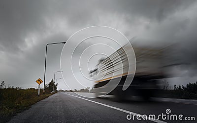 Blurry speed truck running through sharp curve with arrow warning signs. Stock Photo