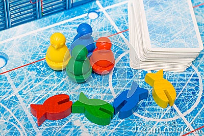 Board game and kids leisure concept - red, yellow, blue, green fish wood chips figure and playing cards in children play. Stock Photo