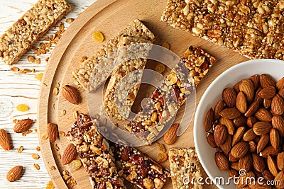 Board with granola bars and bowl with almond on wooden background, top view Stock Photo