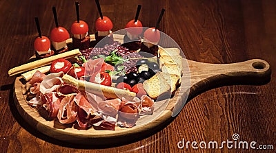 Board with snacks on wooden table. Snacks appetizing served on round board. Restaurant dish concept. Cold appetizers Stock Photo