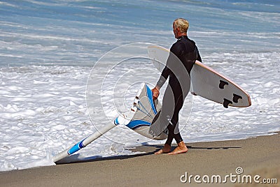 Board surfer hauls in a broken board at Aliso Beach, Laguna Beach, CA. Editorial Stock Photo