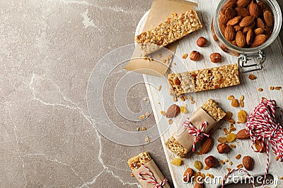 Board with tasty granola bars and nuts on gray background, top view Stock Photo