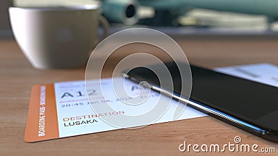 Boarding pass to Lusaka and smartphone on the table in airport while travelling to Zambia. 3D rendering Stock Photo