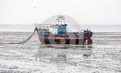 Boat beached on sands at low tide Stock Photo