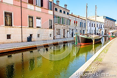 Boat in a canal of the colorful italian village of Comacchio in Stock Photo