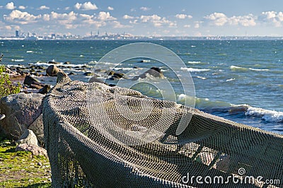 Boat covered by fisherman net at seashore and modern cityscape Stock Photo