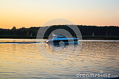 The boat floats on a wide river at sunset Stock Photo