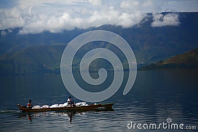 A Boat with goods is sailing in Toba Lake, Samosir Island, North Sumatra, Indonesia. Stock Photo