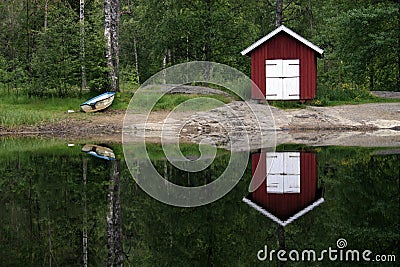 Boat house reflecting on lake Stock Photo