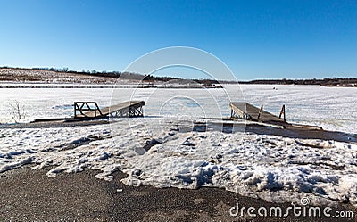 Boat launch ramp at frozen lake with traffic marks on frozen lake surface Stock Photo