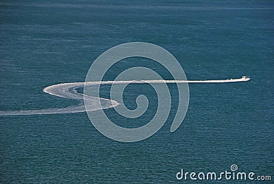 Boat leaving a white 'S' shaped trail on the sea water surface Stock Photo