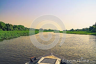 Boat navigating through flooded waters of Pantanal at sunset Stock Photo