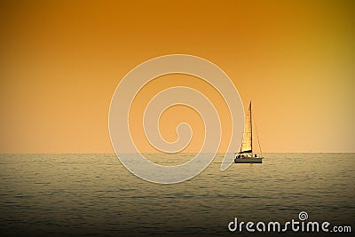 A boat navigating a tranquile sea at sunset time. Dark orange atmosphere. Stock Photo