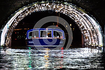 A boat passes through a light filled tunnel in Amsterdam, Nether Stock Photo