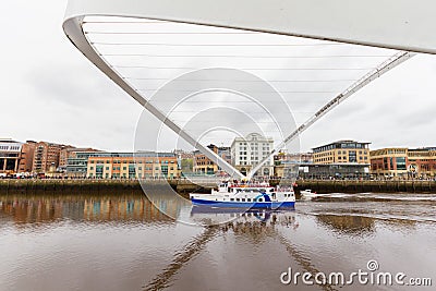 Boat passing under tilted Millennium Bridge in Newcastle, UK Editorial Stock Photo