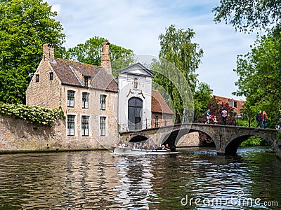 Boat with people, bridge over canal and entrance gate to Begijnhof, Beguinage, in Bruges, Belgium Editorial Stock Photo