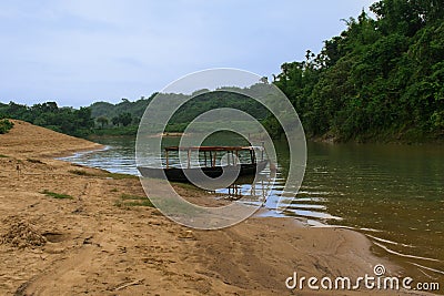 A boat sailed on a bank of a river surrounded by green trees Stock Photo