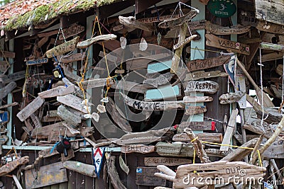 Boat signs and name plates with shells decorating a driftwood hut in Canada`s Inside Passage Stock Photo