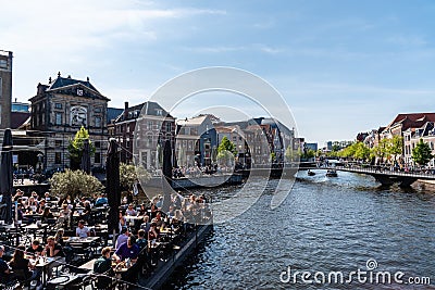 Boat terrace full of people enjoying the sun, food and drinks in the canal of the old town center of Leiden Editorial Stock Photo