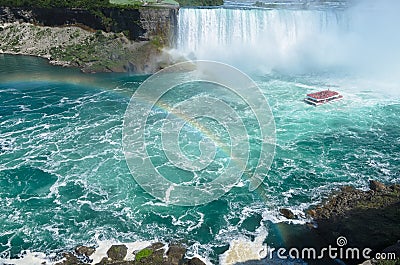 Boat with tourists sailing under the rainbow towards Niagara falls Stock Photo