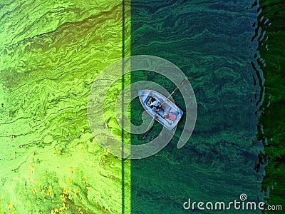 a boat with two sailors floats on green water Stock Photo