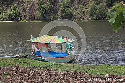 A boat with a unique shape is floating on a clear lake and has a very beautiful view. Jembangan, Kebumen - Indonesia. Good for p Editorial Stock Photo