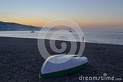 Boat upside down on the beach of Castell de Ferro during a sunrise. Fisherman silhouette, boats in the sea Stock Photo