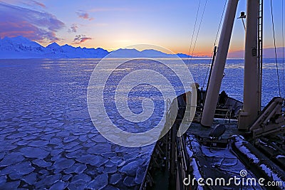 Boat in winter Arctic. White snowy mountain, blue glacier Svalbard, Norway. Ice in ocean. Iceberg twilight in North pole. Pink clo Stock Photo