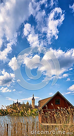 Boathouse with reeds and Schwerin Castle in the background. Vertical panorama with clouds and blue sky Stock Photo