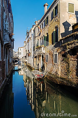 Boats covered from rain parked in the water next to the house in canal of Venice. Stock Photo