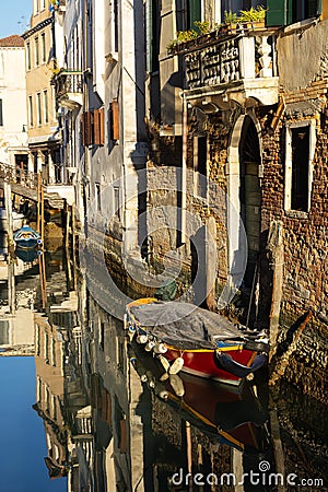 Boats covered from rain parked in the water next to the house in canal of Venice. Stock Photo