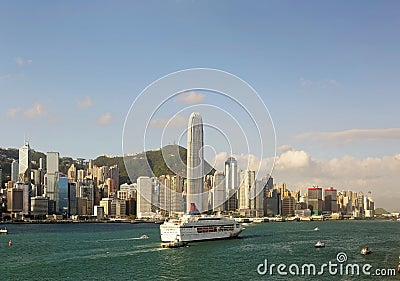 Boats & ferries navigate in Victoria Harbor with the prominent landmark among crowded skyscrapers in Hong Kong Stock Photo