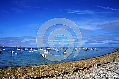 Boats floating in the water near a pebbles beach in Brittany Stock Photo