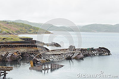 Boats skeleton grunge half buried in sea. Barents Sea. Ship graveyard, Russia, Teriberka Stock Photo