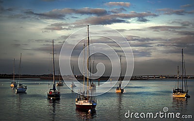 sail boats wait to go into harbor at sunset. Stock Photo