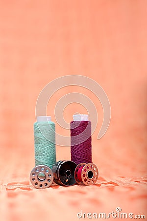 Bobbin case, bobbin and sewing thread on the orange cloth Stock Photo