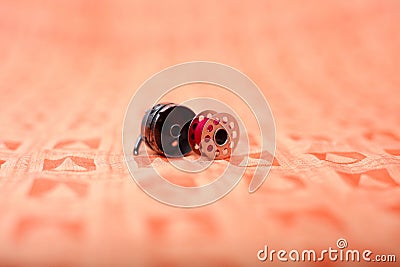 Bobbin case and steel bobbin with pink thread on the orange cloth Stock Photo