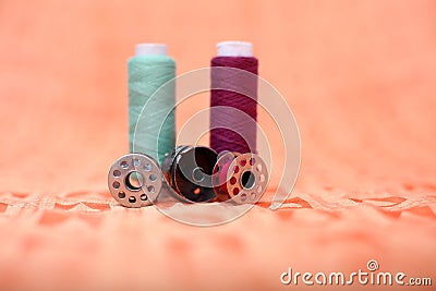 Bobbin case, two bobbin and two sewing thread on the orange cloth Stock Photo