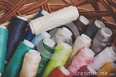 Bobbins thread in willow basket on wooden background Stock Photo