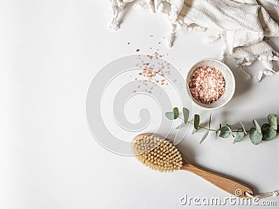 Body brush with wooden handle, white towel and a bowl with pink sea salt on a white background. copy space Stock Photo