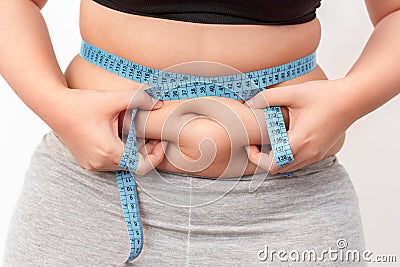 Body Care. Chubby girl with bare belly and tape measure on waist standing isolated on white holding fat fold close-up Stock Photo