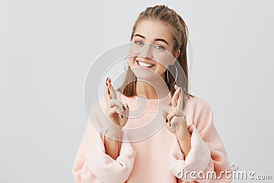 Body language. Superstitious teenager girl with blonde hair and pretty face crossing fingers for good luck, hoping her Stock Photo