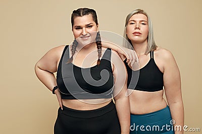 Body Positive. Plus Size Models Portrait. Fat Women In Sportswear On Beige Background. Stock Photo